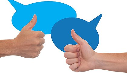 zwei Hände mit dem Handzeichen "Daumen hoch" vor zwei blauen Sprechblasen