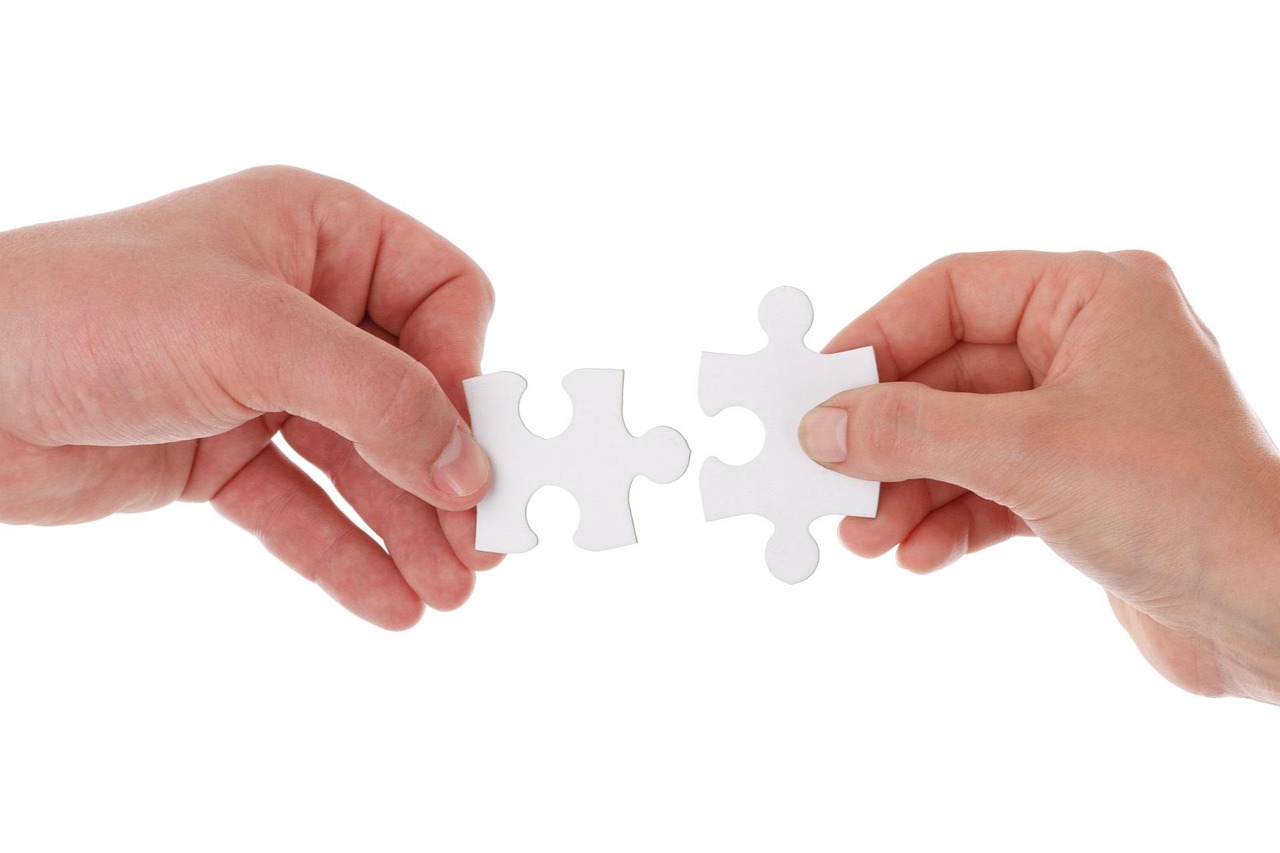 zwei Hände führen zwei Puzzleteile zusammen