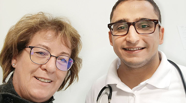 Eine Frau und ein männlicher Arzt lächeln in die Kamera