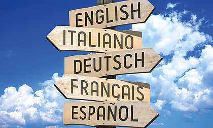 Fünf hölzern Richtungspfeile zeigen in verschiedene Richtungen mit der Aufschrift English, Italiano, Deutsch, Francais, Espanol