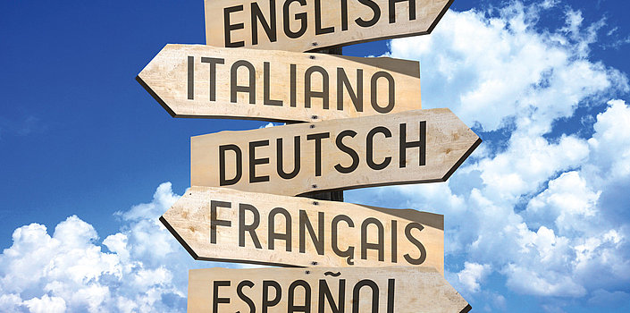 Fünf hölzern Richtungspfeile zeigen in verschiedene Richtungen mit der Aufschrift English, Italiano, Deutsch, Francais, Espanol