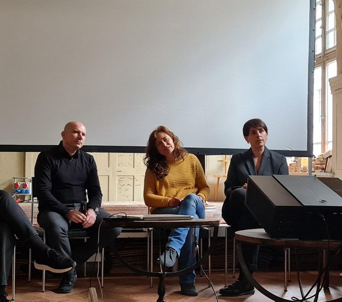 drei Frauen und ein Mann sitzen nebeneinander auf einem Podium