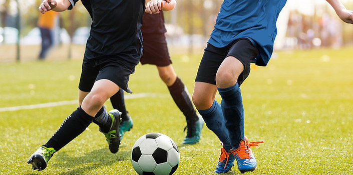 Kinder spielen Fußball auf grünem Rasen