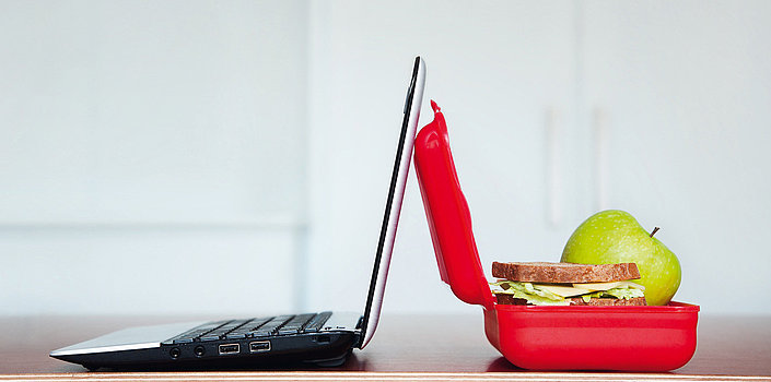 Ein geöffneter Laptop und eine geöffnete gefüllte Butterbrotdose 