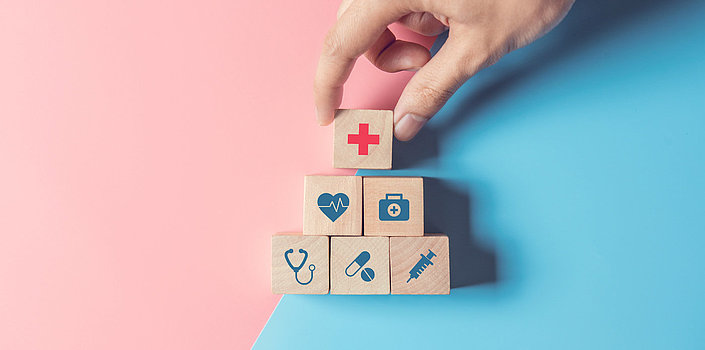 Kleine hölzerne Quadrate mit Symbolbildern für Gesundheit: rotes Kreuz, Herz, Stethoskop, Pillen, Spritzte