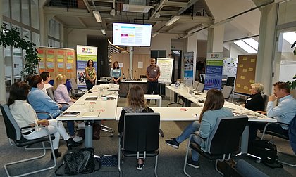 Vortragende und Zuhörende in einem Workshop-Raum