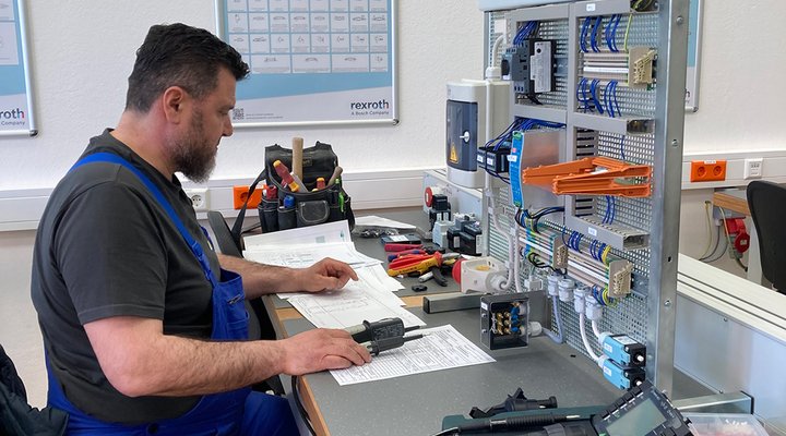 Ein Mann sitzt an einer Werkbank und überprüft elektrische Geräte