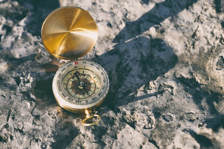 Kompass auf felsigem Untergrund im Sonnenlicht