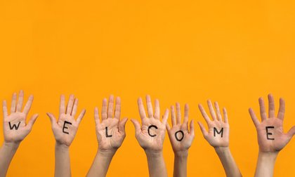 Viele Hände tragen Buchstaben, die zusammen den Schriftzug "Welcome" ergeben.