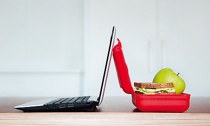 [Translate to English:] Ein geöffneter Laptop und eine geöffnete gefüllte Butterbrotdose 